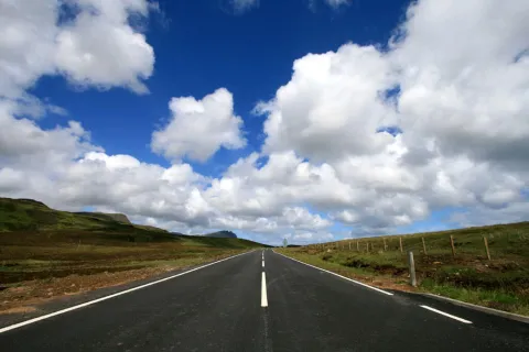 big blue sky with clouds over an open road